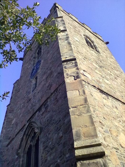The fifteenth-century tower of St Michael & All Angels against a blue sky